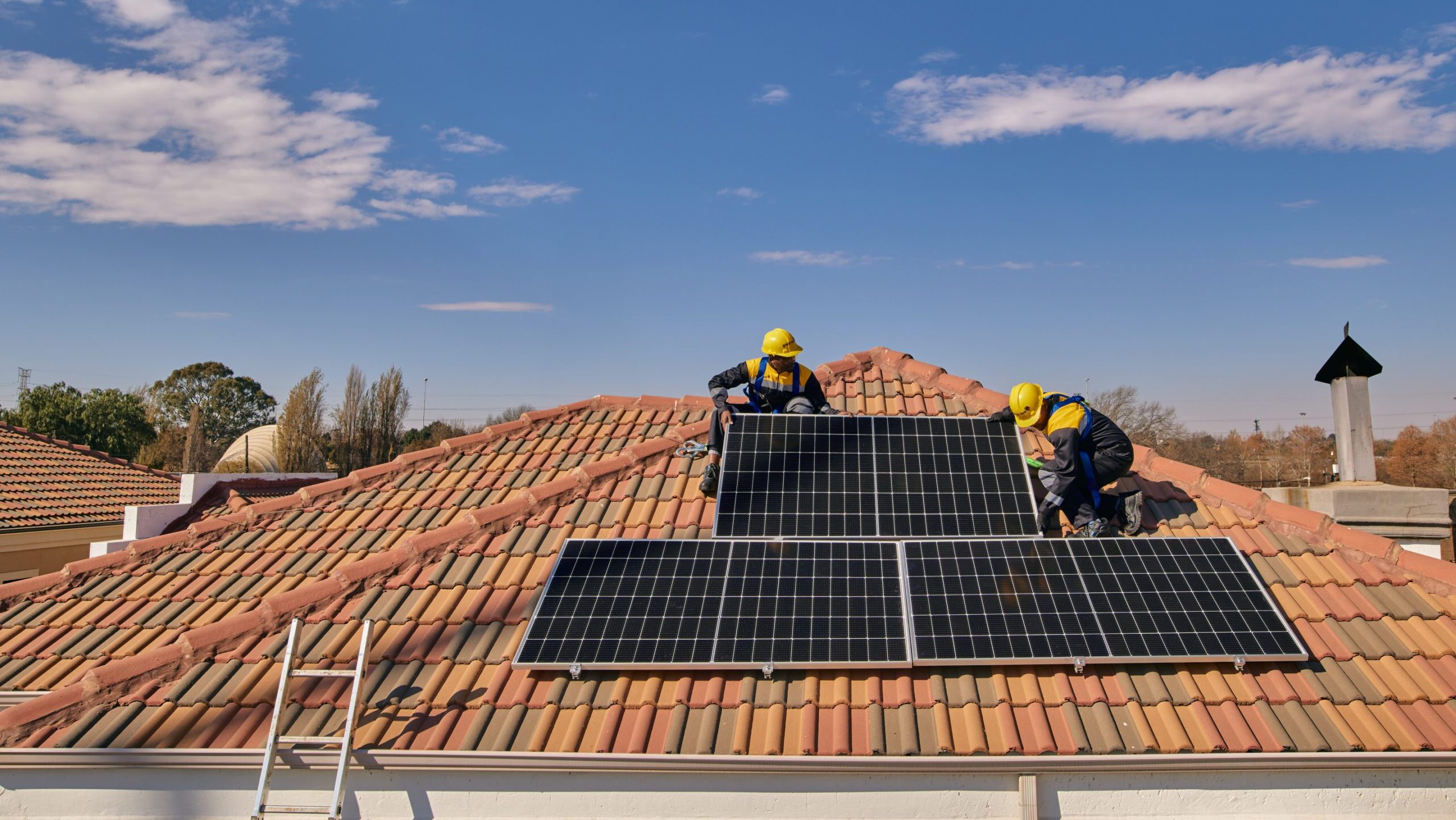 Workers on a tiled roof installing solar panels for a Sun King solar powered rooftop inverter system.