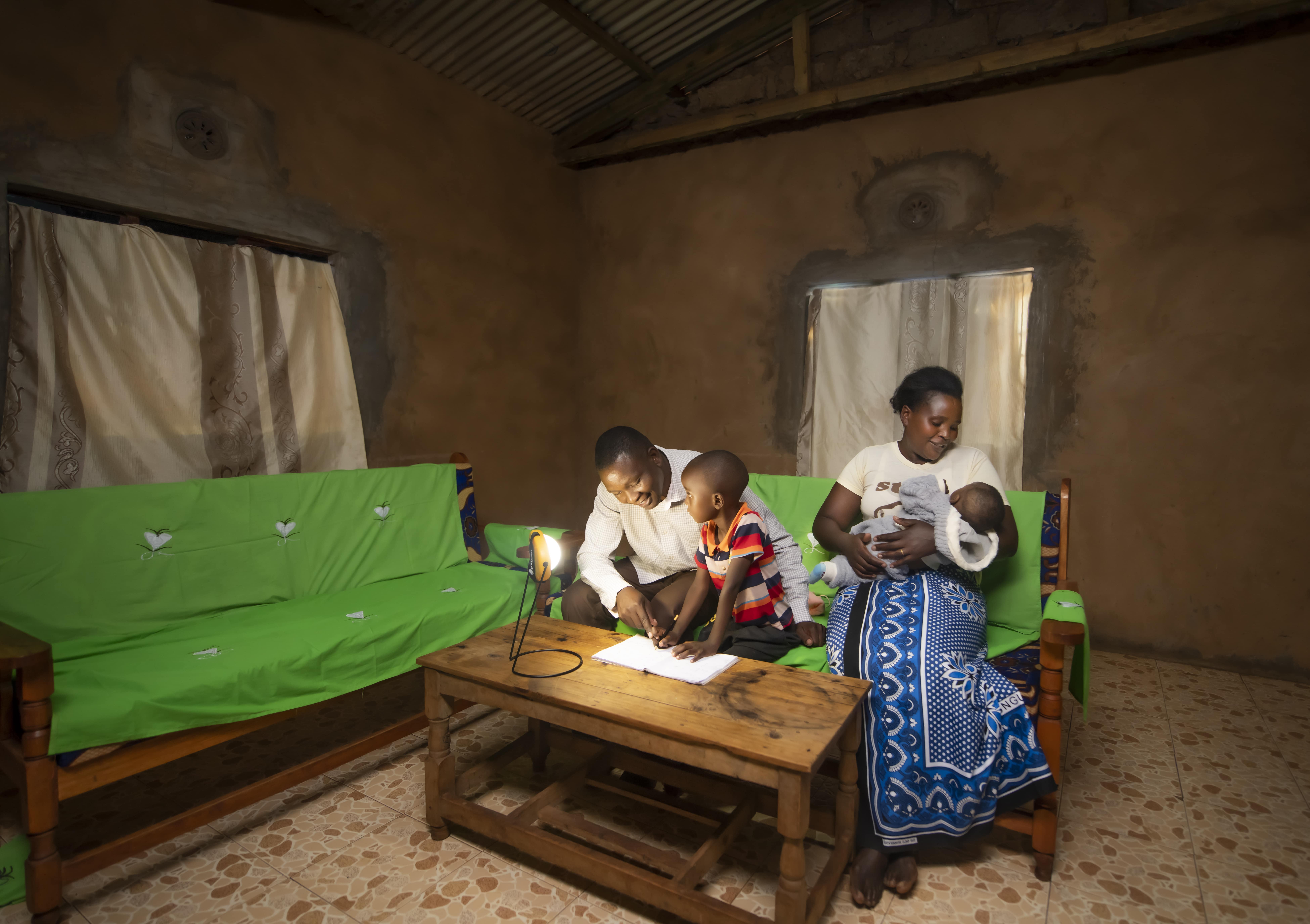 A family uses the affordable solar powered light of the Sun King Boom to study.